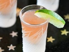 two glasses filled with drinks and lime wedges on top of each glass next to stars