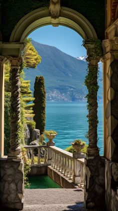 an archway leading to the water with trees on either side and mountains in the background