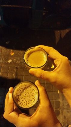 two people are holding glasses with drinks in them