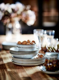 the table is set with plates and bowls full of nuts on top of each other