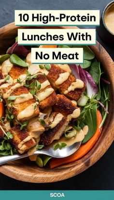 a wooden bowl filled with meat and vegetables on top of a black table next to a spoon