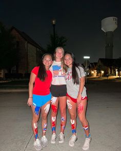 three girls are posing for the camera in front of an old water tower at night