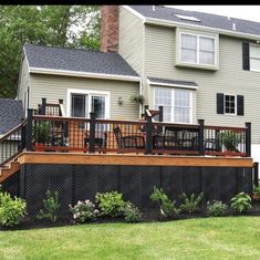 a house with a deck in the front yard and some plants on the back porch