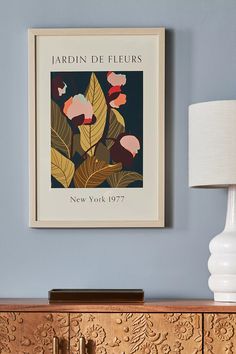 an art print hangs on the wall above a dresser with a lamp and sideboard