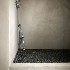 a shower head and hand held showerhead in a bathroom with stone flooring on the walls