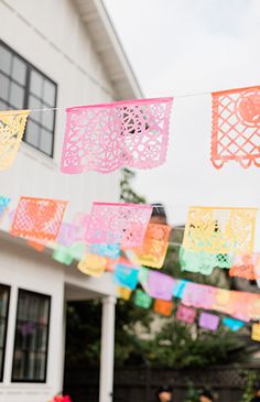 colorful paper cutouts are hanging from a clothes line on a house's front porch