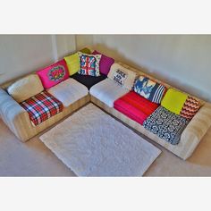 a multicolored couch with pillows on it in the corner of a living room