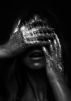 a woman holding her hands to her face covered with glitter in front of her eyes