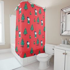 a red shower curtain with christmas trees on it in a bathroom next to a toilet