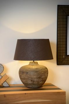 a lamp sitting on top of a wooden table next to a framed photo and letter