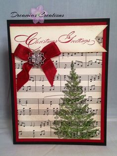 a christmas card with a red ribbon and a green tree on it, in front of a sheet of music