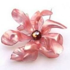 a pink flower brooch sitting on top of a white table