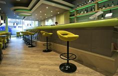 yellow bar stools in front of a counter with bottles on it