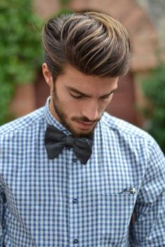 a man wearing a bow tie looking down at his cell phone