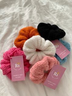 four skeins of yarn sitting on top of a white bed with tags attached to them