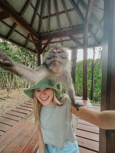 a woman is holding a monkey on her head while another person holds it in the air