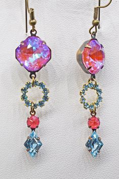 Pink and blue pastels create such a feminine look.   The pink stones are called electric lotus pink and the blue is aquamarine.  The pink stones are very unique and have a brilliant shine.  These earrings are made up of 3 sections.  First the square shaped pink rhinestone, then the blue round rhinestone drop and finally the combined pink and blue rhinestone drop.  Just lovely.   Arrives nicely packaged and ready for gift giving if desired.  Measurements: The length is 2" and does not include the ear wire length The width is a bit over 1/2" Pink Stones, Wedding Jewelry Earrings, Handcrafted Earrings, Pink Rhinestones, Earrings Blue, Pink Stone, Blue Rhinestones, Feminine Look, Blue And Pink