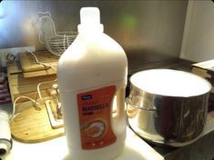 a bottle of liquid sitting on top of a counter next to a pot and pan