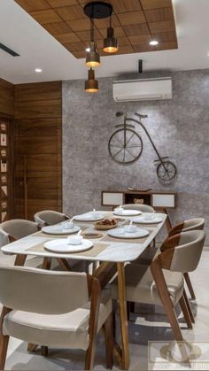 a dining table with chairs and plates on it in front of a bike mounted to the wall