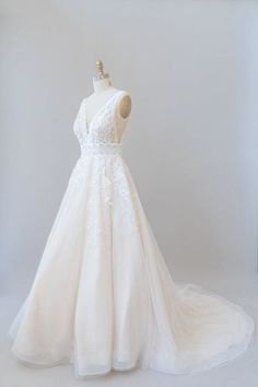 a white wedding dress is on display in a room with a mannequin's head