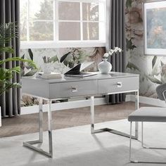 a white desk sitting in front of a window next to a chair and potted plant