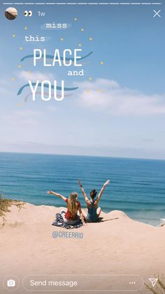 two people sitting on the beach with their arms in the air