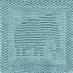 a blue knitted square on top of a white surface with the center stitched in