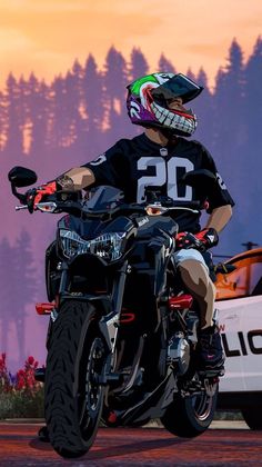 a man riding on the back of a motorcycle in front of a police car at sunset