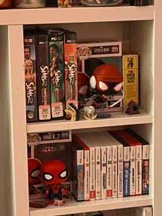 a book shelf filled with lots of books next to a wall mounted spiderman figure