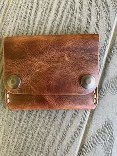 This handmade leather wallet offers three inner pockets with a snap closure.  Measurements: 102 mm X 80 mm when snapped 102 mm X 149 mm when open -- [ CARE INSTRUCTIONS ] -- * Remove dust and dirt with a soft brush or cloth. * Refrain from using detergents or chemicals. Use a damp cloth to wipe your wallet lightly and allow to air dry. * Allow them to dry naturally and never under an artificial heat source. * If the leather gets too dry, apply a neutral leather cream or conditioner on the wallet to moisturize the leather. *Please note colors may vary slightly. We try to capture the colors the best we can.* If you have any questions, please do not hesitate to contact me. Rectangular Trifold Wallet With Snap Closure As Gift, Handmade Brown Wallet For Everyday Carry, Bifold Coin Purse With Snap Closure, Hand-stitched Trifold Wallet For Everyday Use, Rustic Leather Wallets With Card Slots, Everyday Hand-stitched Trifold Wallet, Hand-stitched Trifold Wallet, Brown Rectangular Trifold Wallet With Waxed Finish, Brown Wallet With Snap Closure As Gift