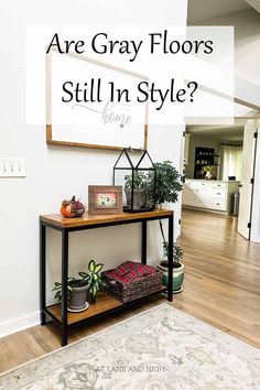 a living room with white walls and wood flooring that says are gray floors still in style?