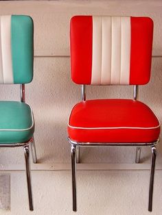 two red and blue chairs sitting next to each other on top of a white wall