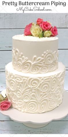 a three tiered white cake with pink flowers on top and the words pretty buttercream piping above it