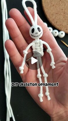 a hand holding a small white crocheted skeleton