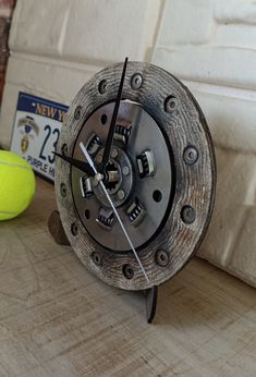 a close up of a clock on a table with a tennis ball in the background