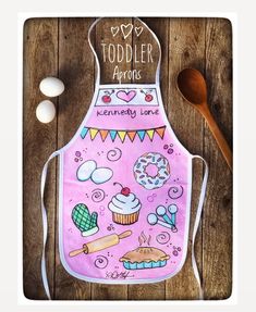 a pink apron that says toddler aprons with cupcakes and baking utensils