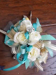 a bridal corsage with white roses and blue ribbons on a wooden table