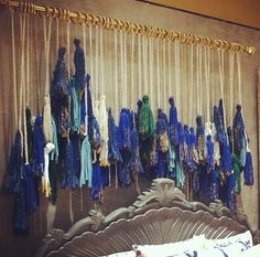 there is a bed with blue and green scarves hanging on the wall