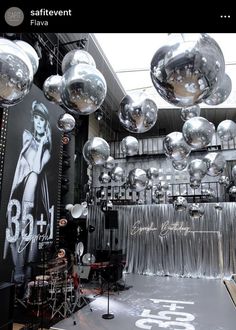 a room filled with lots of shiny silver balloons hanging from the ceiling next to a stage