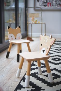 two children's wooden chairs sitting on top of a black and white rug