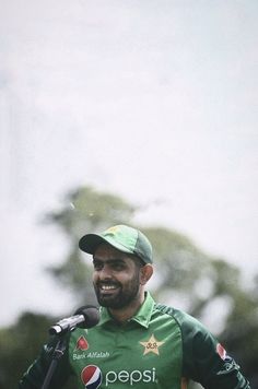 a man standing in front of a microphone and wearing a green shirt with the word pepsi on it