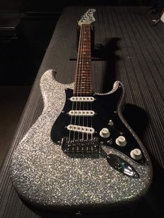 an electric guitar sitting on top of a table covered in silver flecky glitter