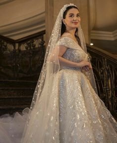 a woman in a wedding dress standing on the stairs with her veil draped over her head