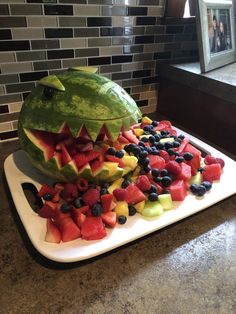 a watermelon shaped like a dinosaur with fruit in it's mouth on a tray