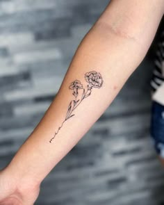 a woman's arm with a small flower tattoo on the left side of her arm