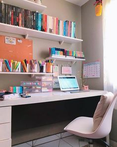 a white desk topped with a laptop computer next to a book shelf filled with books