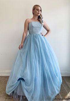 a woman in a blue dress standing against a wall