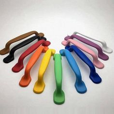 a group of colorful plastic spoons sitting on top of a white table next to each other