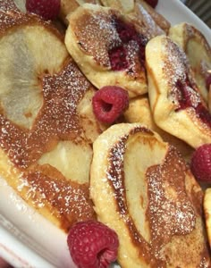 pancakes with raspberries and powdered sugar on a white plate, ready to be eaten