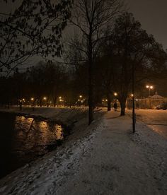 a snowy path next to a river at night